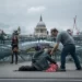 A man giving some change to a homeless man sitting on the floor