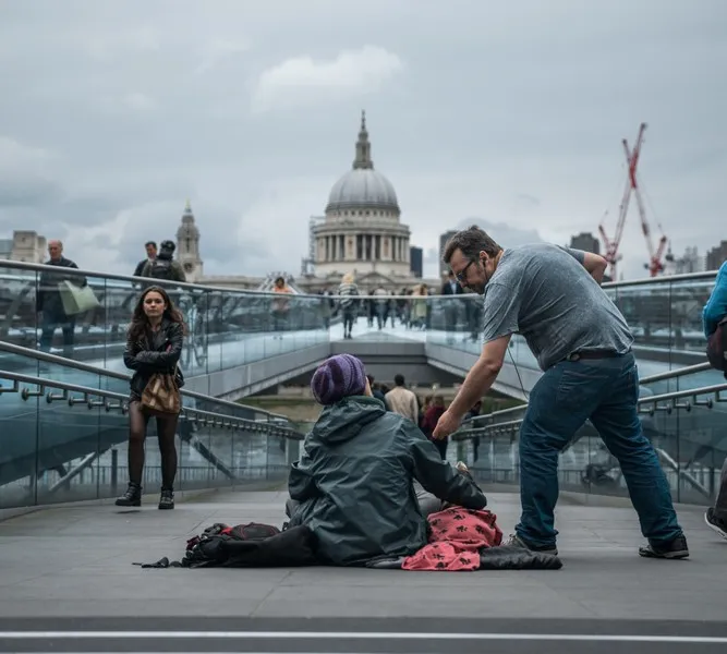 A man giving some change to a homeless man sitting on the floor