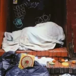 A homeless person in a doorway under a blanket ecperiencing stigmatisation
