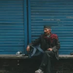 A refugee sitting on a wall