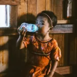 A young child drinking water from a plastic bottle
