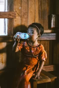 A young child drinking water from a plastic bottle