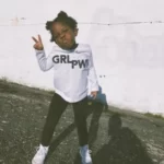 A young black girl wearing a tshirt which reads 'grl pwr'.