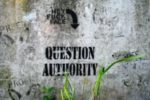 Grafitti on a grey wall which reads 'question authority'