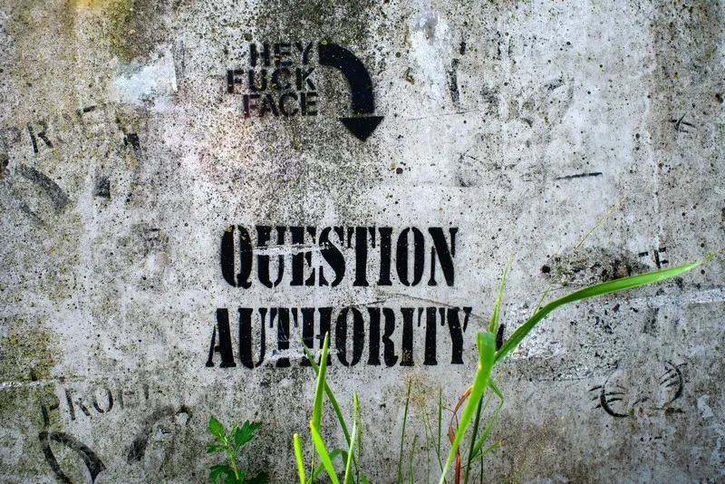 Grafitti on a grey wall which reads 'question authority'