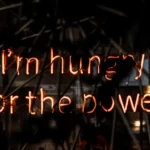 neon lights in fire colours - reads 'i'm hungry for the power'