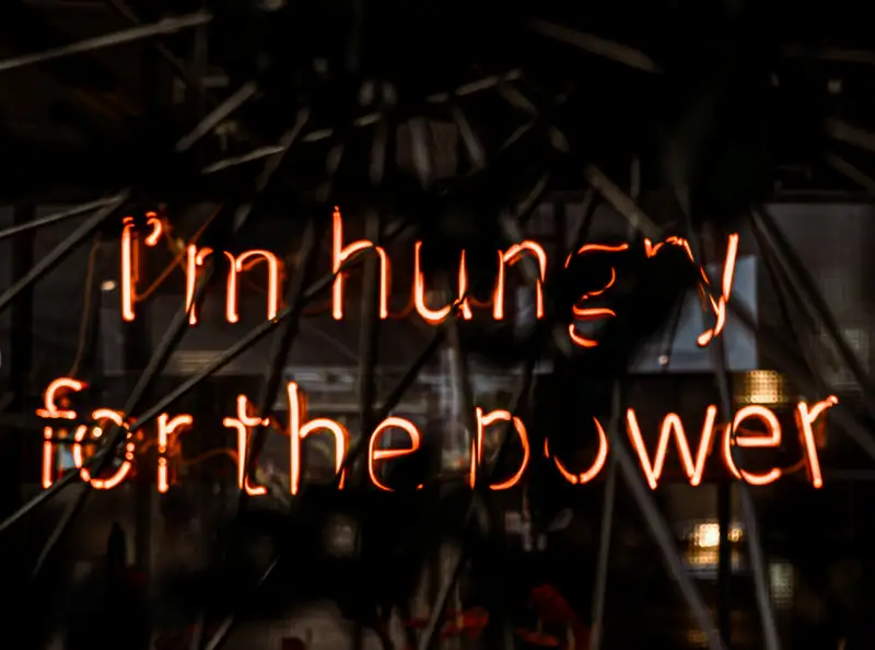 neon lights in fire colours - reads 'i'm hungry for the power'
