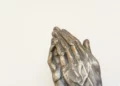 two hands of a metal religious statue praying