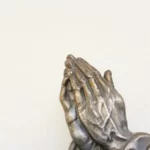 two hands of a metal religious statue praying