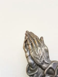 two hands of a metal religious statue praying