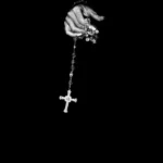 A hand holding a cross necklace against a black background