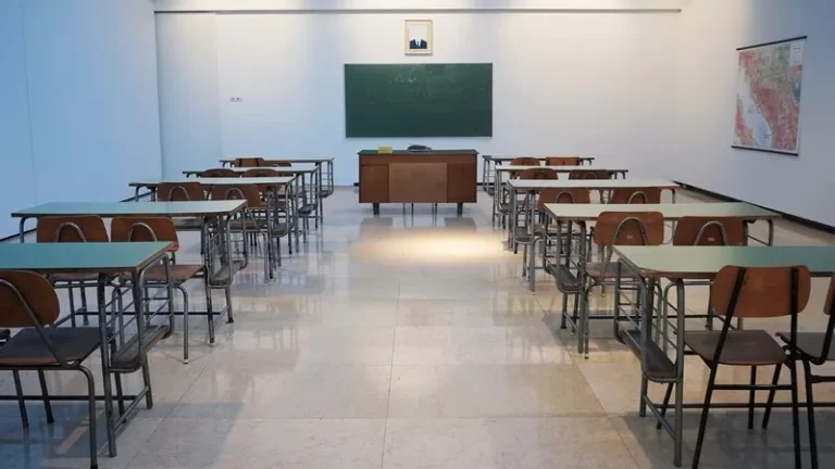 An old fashioned classroom with a blackboard and two columns of desks