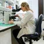 A scientist practicing her vocation in the laboratory through a microscope