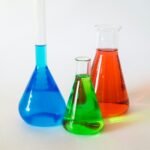 three science flasks with blue green and red liquids