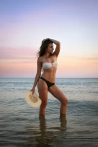 A woman wearing a bikini posing on a beach