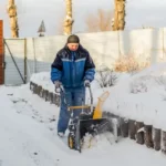 A man clearing snow using a road gritting machine