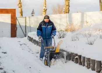 A man clearing snow using a road gritting machine