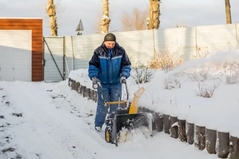 A man clearing snow using a road gritting machine