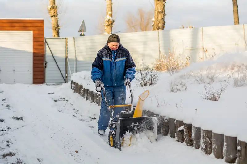 A man clearing snow using a road gritting machine