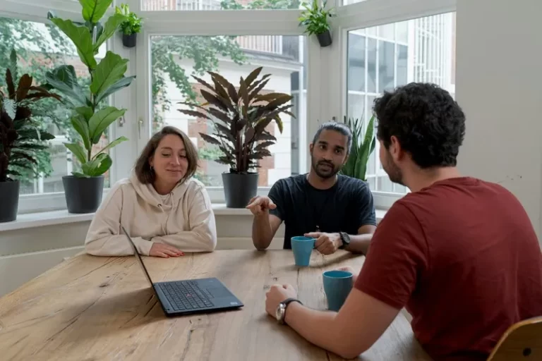 a group of stakeholders sitting around a table with a laptop
