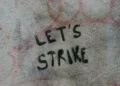 A dirty wall with the words 'let's strike' written on it