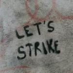 A dirty wall with the words 'let's strike' written on it