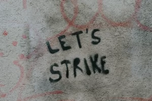 A dirty wall with the words 'let's strike' written on it