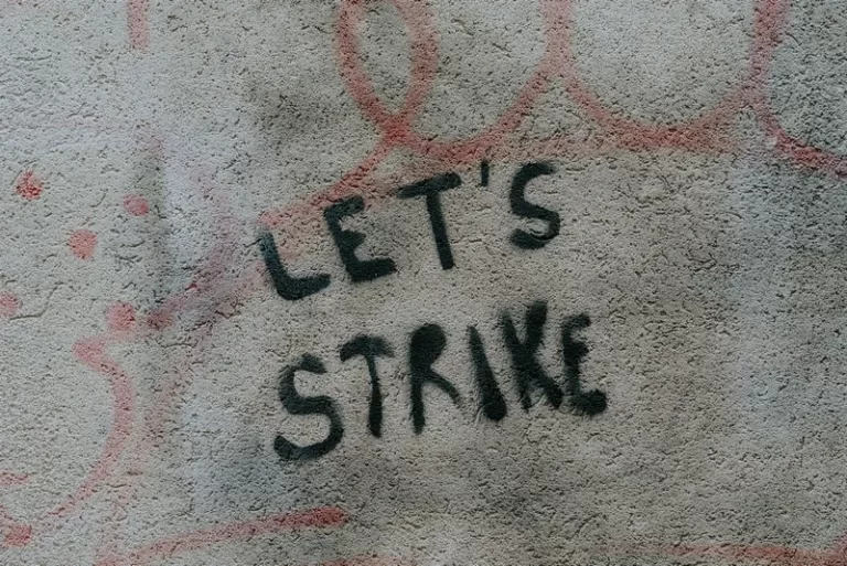 A dirty wall with the words 'let's strike' written on it
