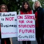 A group of teachers on strike with placards stating: education is not a business and on strike for our students future.