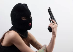 A woman dressed as an armed robber with balaclava and gun - symbolic violence and gender
