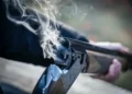 The Barrell of a just fired shotgun with smoke exiting - symbolic violence media