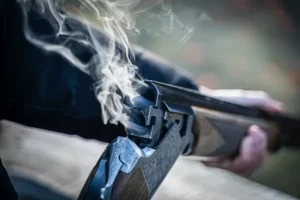 The Barrell of a just fired shotgun with smoke exiting - symbolic violence media