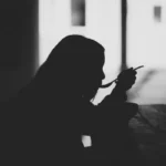 A silhouette of a woman eating with a spoon