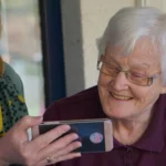 A carer helping to keep an older person entertained with a phone