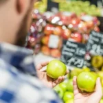 A man holding two apples the same indicating the lack of consumer choice