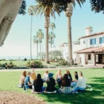 A group of people sitting in a circle at a commune on a sunny day