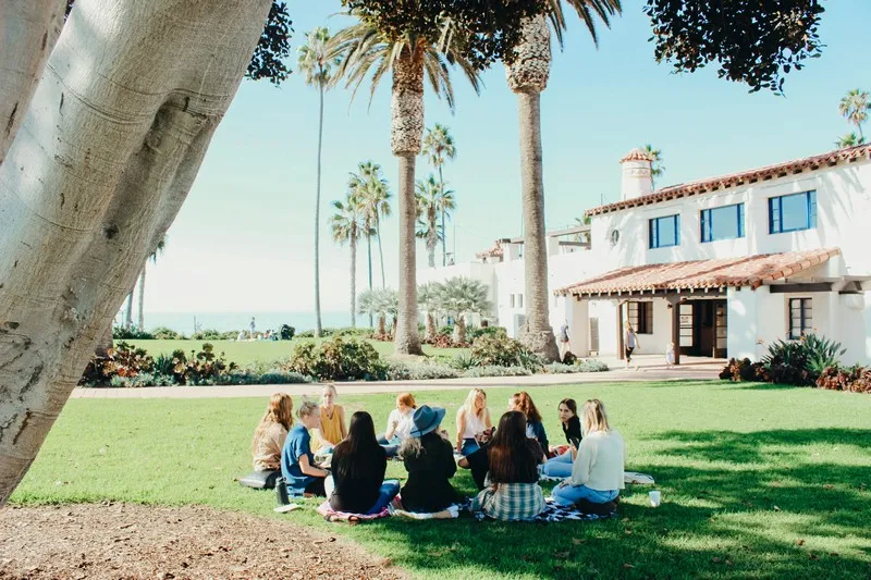 A group of people sitting in a circle at a commune on a sunny day