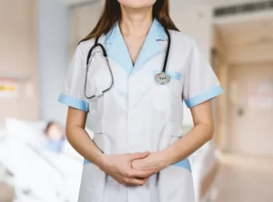 A nurse with a stethoscope around her neck and hands folded.