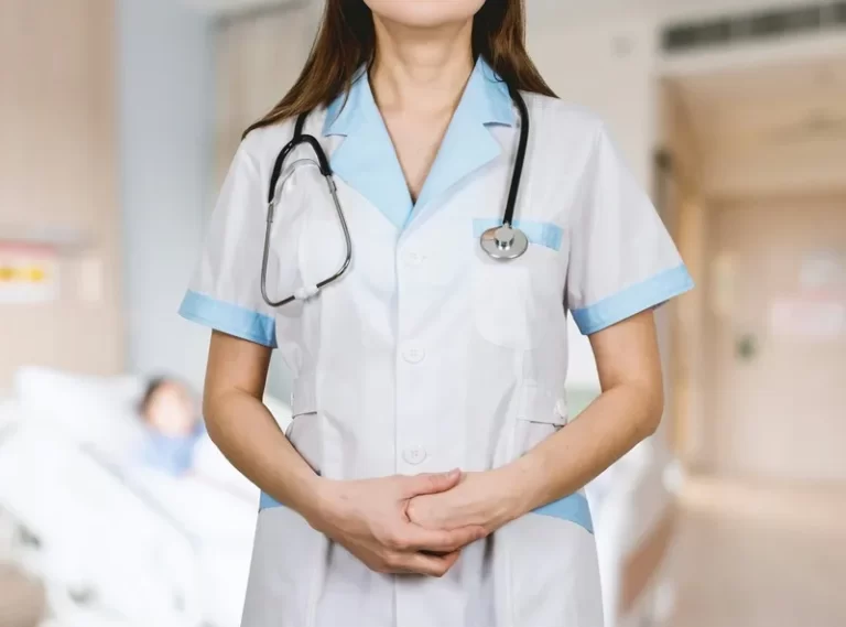 A nurse with a stethoscope around her neck and hands folded.