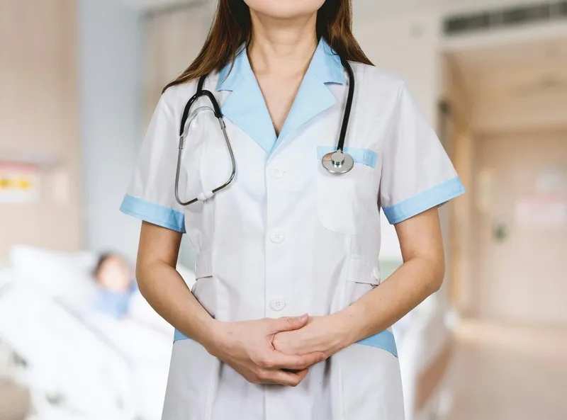 A nurse with a stethoscope around her neck and hands folded.