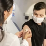 A man wearing a mask and receiving an injection