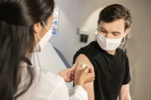 A man wearing a mask and receiving an injection