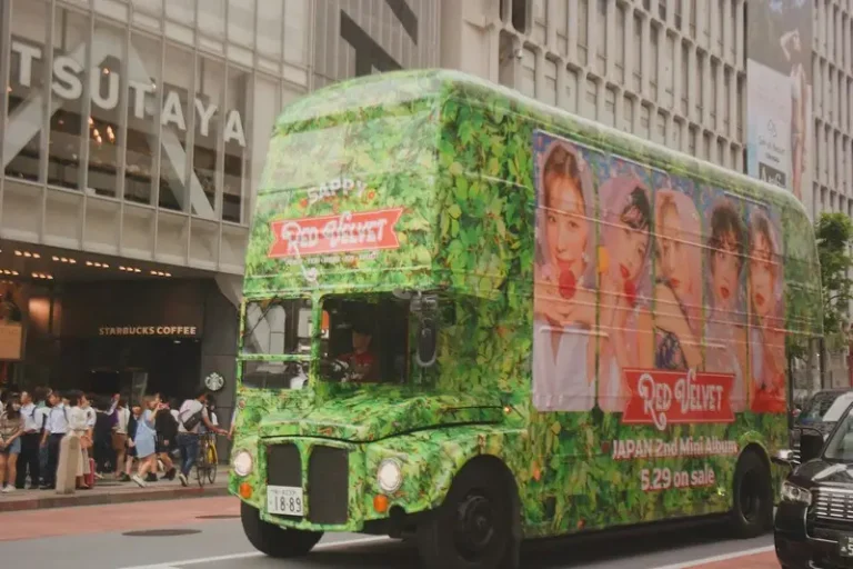 A green bus with members of a K-Pop band on the side