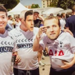 A group of football hooligans holding mask cut outs over their faces