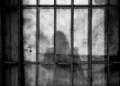 the silhouette of a person behind bars in a jail cell