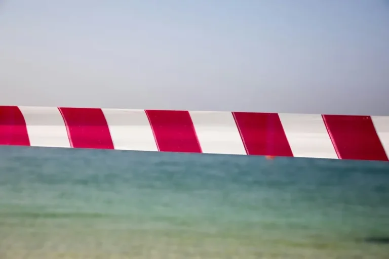 A line of red and white tape separating sky from beach to indicate taboo, censorship, or forbidden