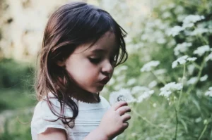 A young girl blowing a flower