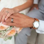 A couple engaging in conjugal roles by getting married. Hands are visible with wedding rings and flowers.
