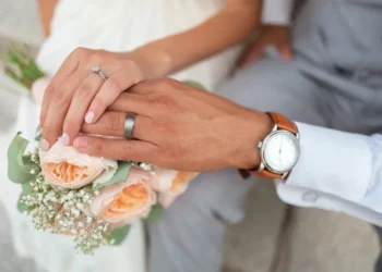 A couple engaging in conjugal roles by getting married. Hands are visible with wedding rings and flowers.