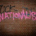 A brick wall with grafitti that reads 'fuck nationalism'.